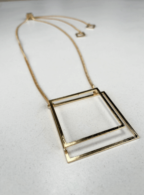Collana geometrica quadrato BIG in ottone con rifinitura in oro chiaro satinato ciondolo a doppio quadrato grande e catena grumetta a lunghezza regolabile attraverso il cursore che lascia cadere dietro la schiena i pendenti