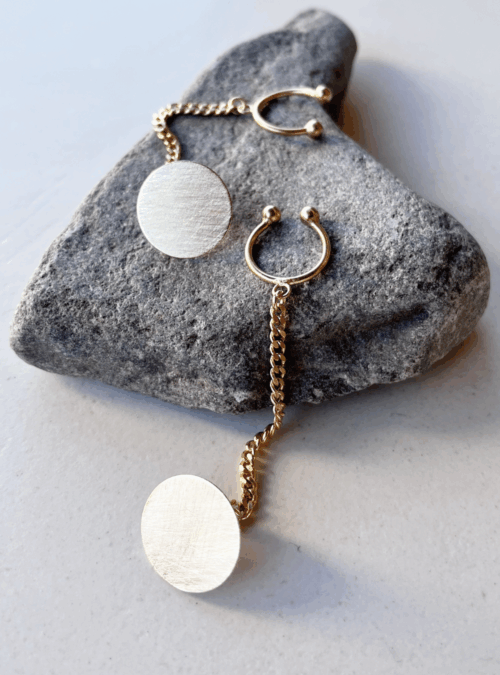 Orecchini ear cuffs catena in ottone con rifinitura in oro chiaro satinato con chiusura a farfallina e catena collegata con annellina per essere applicata al padiglione dell'orecchio. Orecchini tondi al lobo minimali e contemporanei