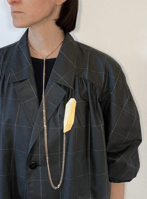 Collana geometrica OMBRA SOTTILE artigianale in ottone con rifinitura in oro chiaro satinato catena grumetta che scorre attraverso un'anella e moschettone all'estremità che si aggancia alla spilla creando un effetto di orologio da taschino. La catena può essere estratta.