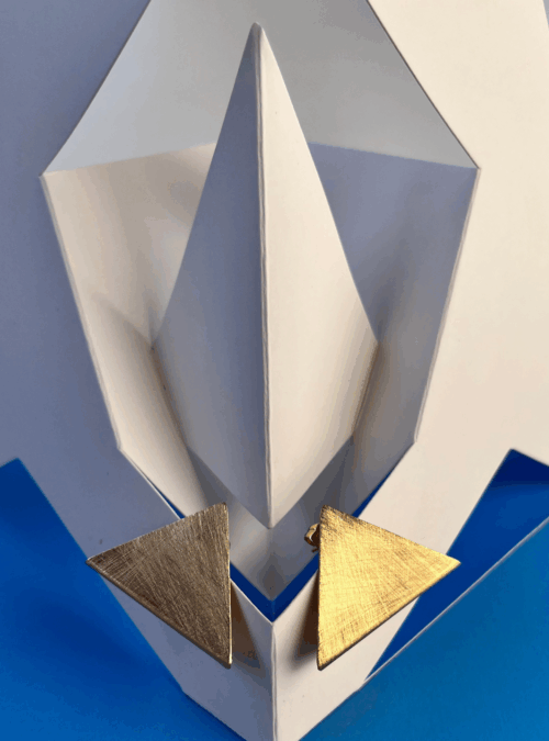 Orecchini SIMMETRIA MOMENTANEA in ottone con rifinitura in oro chiaro satinato e graffiato ispirati alle sculture da viaggio di Bruno Munari, leggeri a forma triangolare e piegati cambiano forma in base al movimento del collo.
