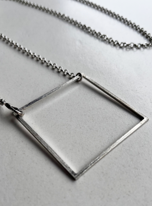 Collana geometrica quadrato argento in ottone con rifinitura in argento satinato, catena lunga rolò che consente una regolazione agganciando il moschettone alla lunghezza desiderata. Collana multi indossabile sia lunga che a girocollo con ciondolo quadrato grande
