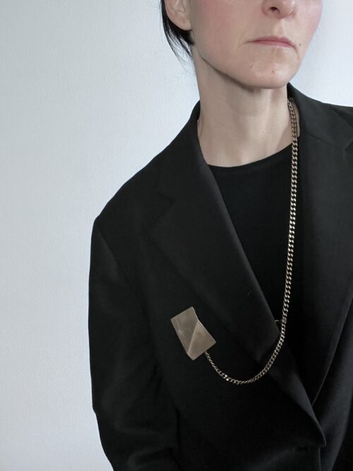 Collana spilla su e giù artigianale in ottone con spilla collegata alla catena che crea l'effetto dell'orologio da taschino estraibile e intercambiabile dalla forma rettangolare ispirata alle sculture da viaggio di Bruno Munari