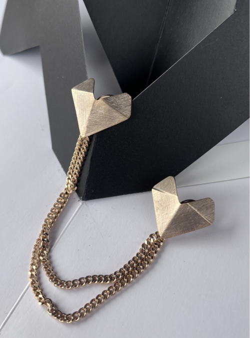 Doppia spilla artigianale “Cuore Minimo” in ottone con finitura oro chiaro satinato, due cuori geometrici ispirati agli origami collegati da doppia catena grumetta.