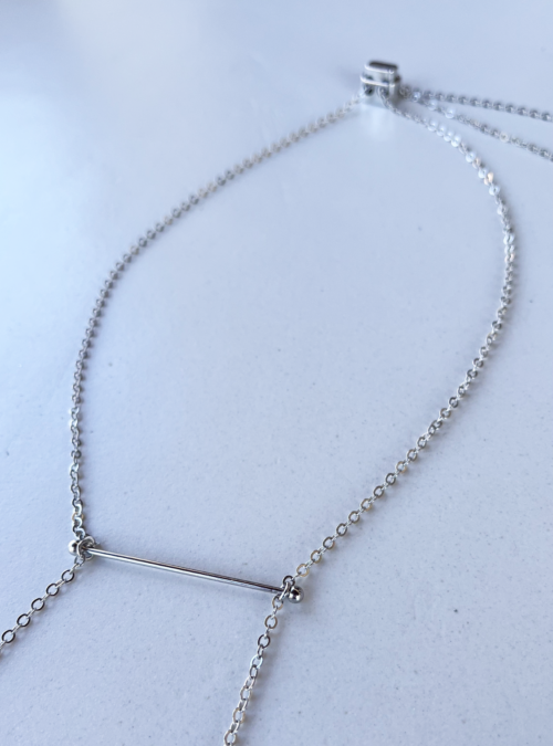 Collana piercing2 argento in ottone con rifinitura in argento lucido, centrale costruito in filo in stile piercing dal quale cadono due ciondoli. dietro la schiena c'è un cursore per regolare la lunghezza lasciando cadere altri due ciondoli a cerchio in filo.