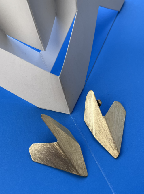 Orecchini CUORE LOGICO in lamina di ottone con rifinitura in oro chiaro satinato dalla forma a cuore geometrico asimmetrica fatta di piegature della superficie. Orecchini ispirati alle sculture da viaggio di Bruno Munari.
