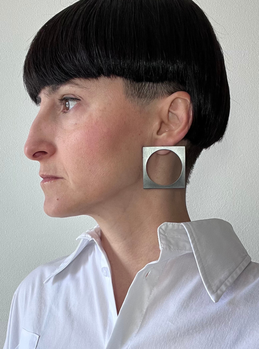 Orecchini quadrato black big a perno artigianali in ottone con finitura black satinato. La forma geometrica è minimalista, composta da un quadrato nero con un cerchio ritagliato al centro e chiusura a farfallina sul retro.