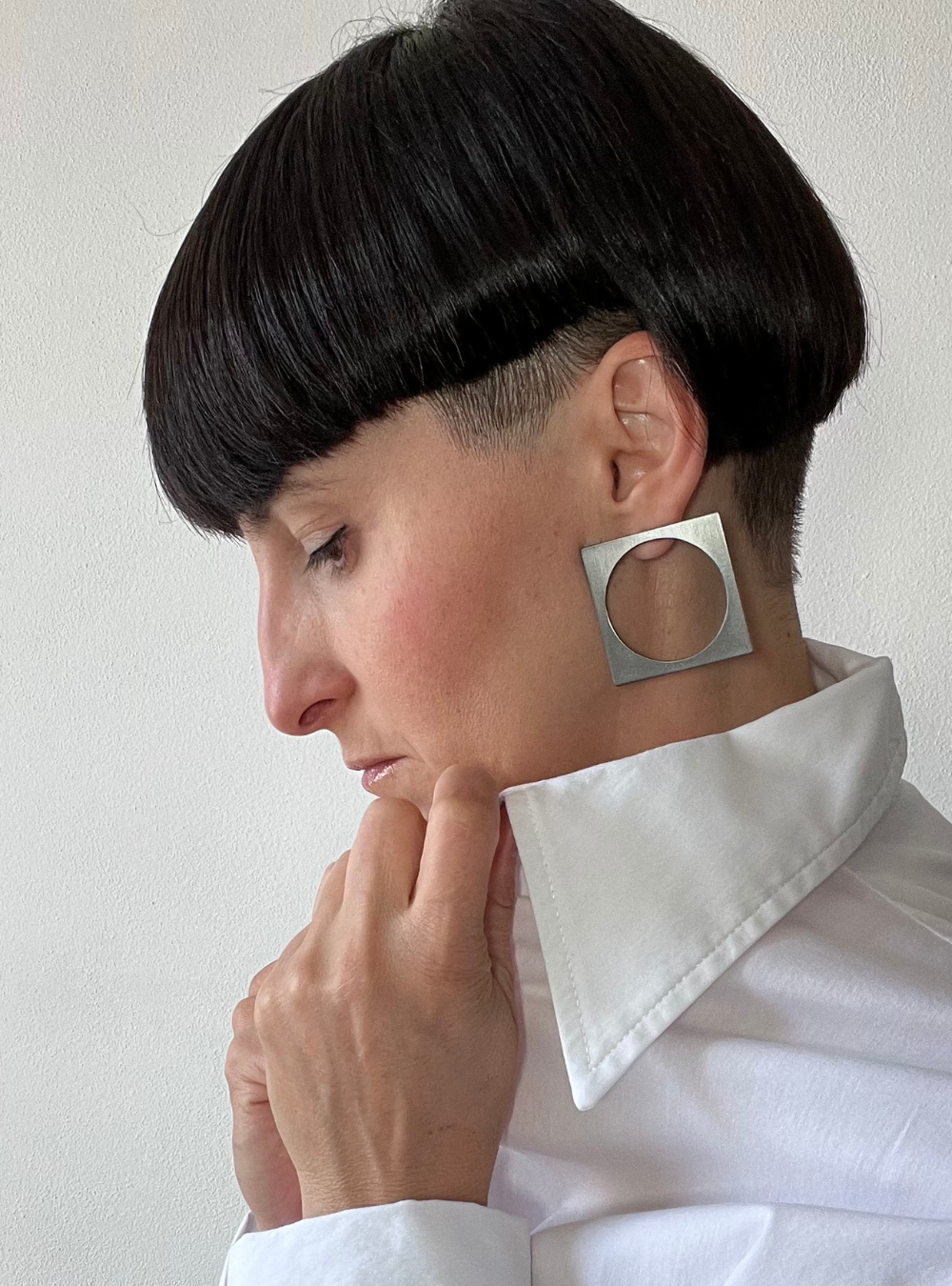 Orecchini quadrato black big a perno artigianali in ottone con finitura black satinato. La forma geometrica è minimalista, composta da un quadrato nero con un cerchio ritagliato al centro e chiusura a farfallina sul retro.