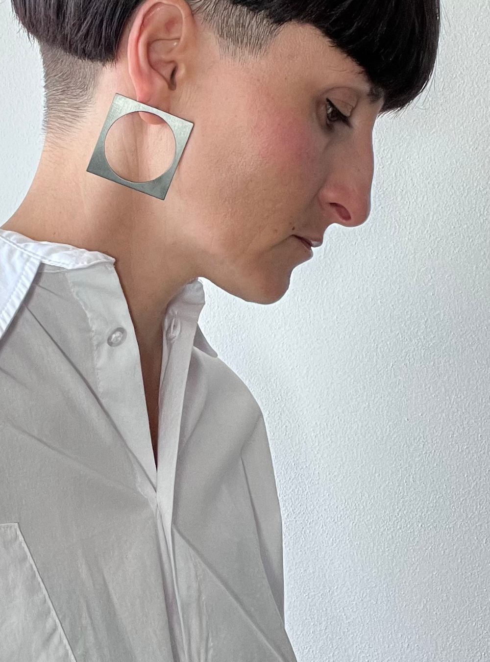 Orecchini quadrato black big a perno artigianali in ottone con finitura black satinato. La forma geometrica è minimalista, composta da un quadrato nero con un cerchio ritagliato al centro e chiusura a farfallina sul retro.
