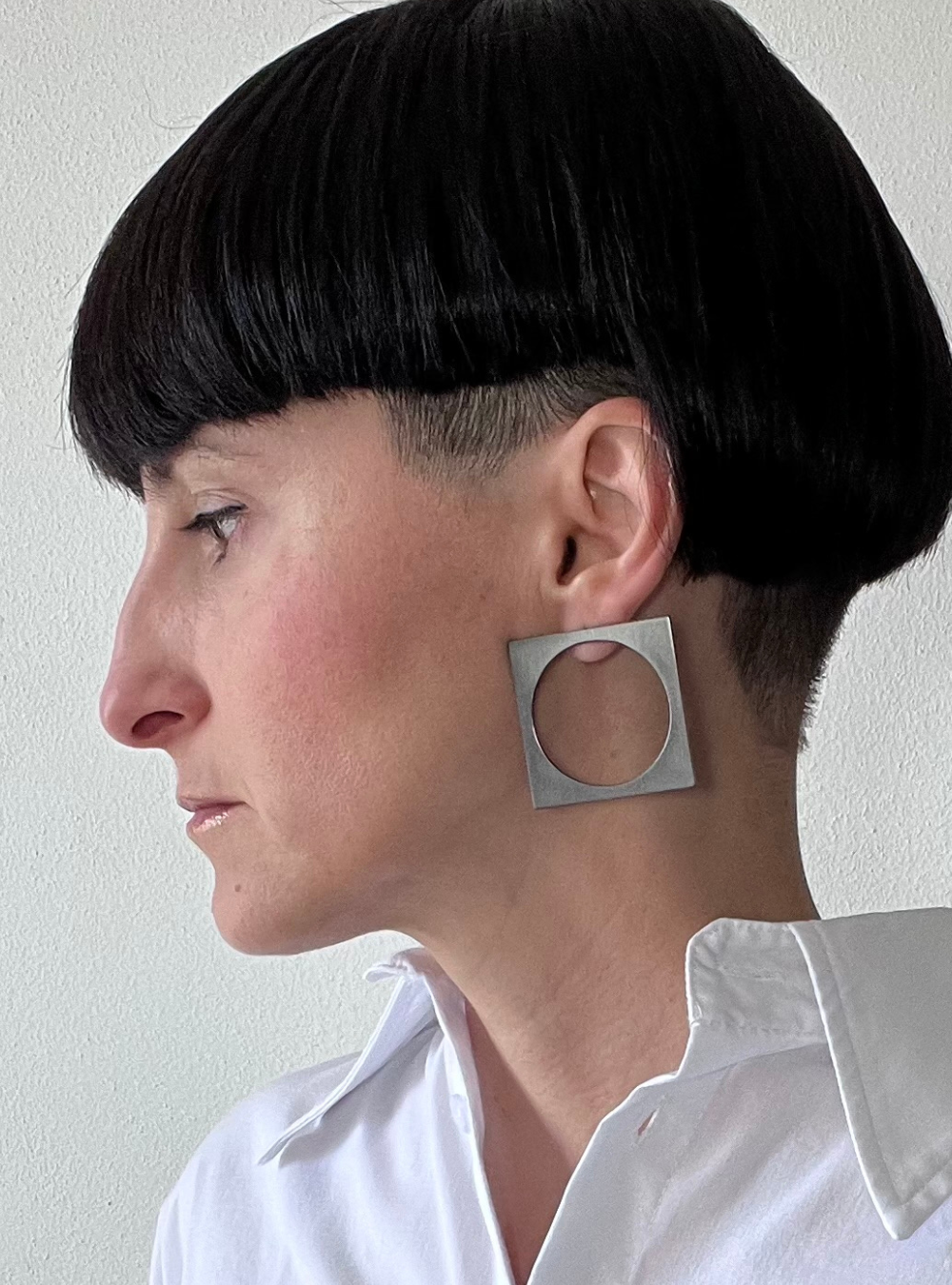 Orecchini quadrato black big a perno artigianali in ottone con finitura black satinato. La forma geometrica è minimalista, composta da un quadrato nero con un cerchio ritagliato al centro e chiusura a farfallina sul retro.
