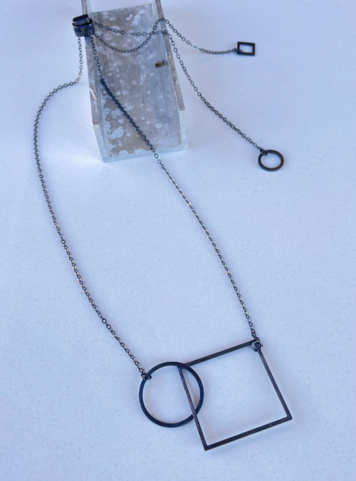 Collana cerchio quadrato black artigianale in ottone con rifinitura in black satinato dal sapore contemporaneo con catena lunga regolabile attraverso il cursore che lascia cadere i ciondoli dietro la schiena.